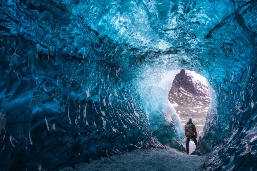 coolcation-iceland A traveler exploring an ice cave in Iceland during the summer, highlighting the rising global coolcation trend and sustainable tourism.